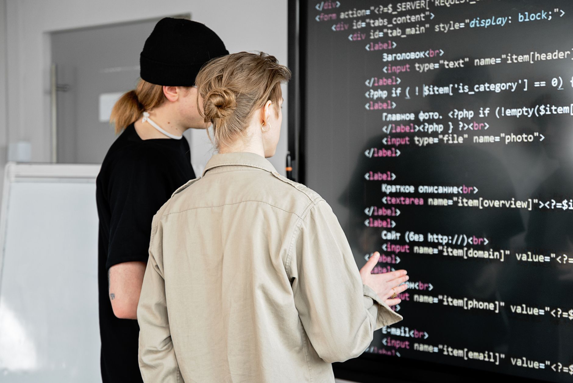 responsable informatique testant un logiciel écran interactif dans une salle professionnelle, avec tableau de compatibilité et paramètres de sécurité affichés à proximité